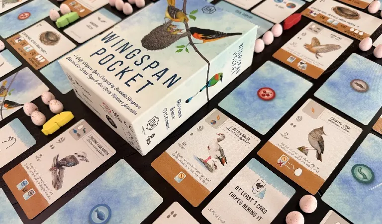 A box labeled "Wingspan Pocket" with illustrations of birds and a nest on a branch. Surrounding the box are game cards featuring bird illustrations, eggs, and buttons. Some cards have visible text such as "AT LEAST 1 CARD TUCKED BEHIND IT", "STARTING HERE, ACTIVATE", and "PLAY A BIRD".