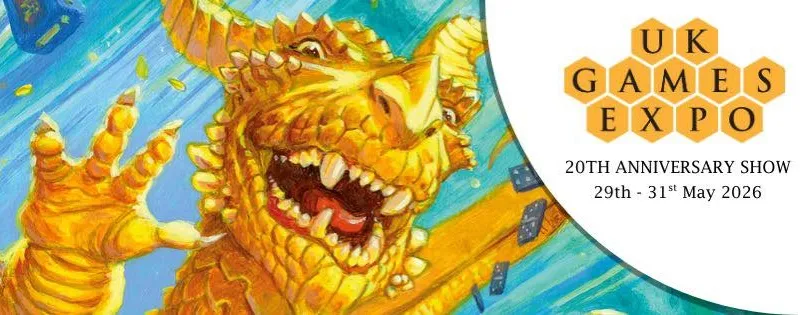 A vibrant illustration features a large, golden dragon with a playful expression, showcasing its sharp teeth and prominent features. The dragon is surrounded by a blue background with scattered game dice, emphasizing a whimsical and dynamic atmosphere. The UK Games Expo logo is prominently displayed in the corner, indicating the event's 20th anniversary from May 29th to 31st, 2026.