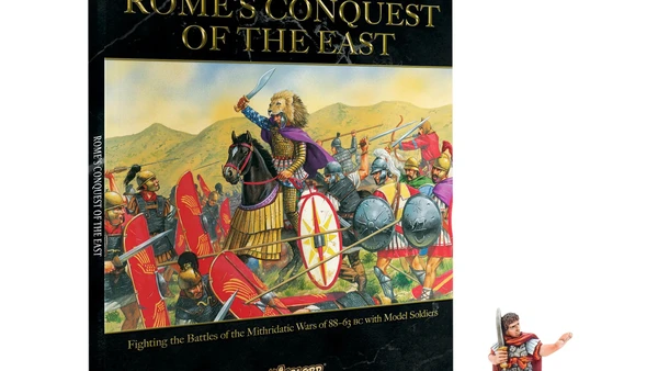 A book titled "Rome's Conquest of the East" from the Hail Caesar series is prominently displayed, featuring a colorful illustration of ancient warriors in battle, including a mounted figure in a purple cloak. The book cover includes the subtitle "Fighting the Battles of the Mithridatic Wars of 88-63 BC with Model Soldiers." Next to the book, there is a miniature figure of Julius Caesar, depicted in early Roman armor, holding a sword and standing on a small base with grass.