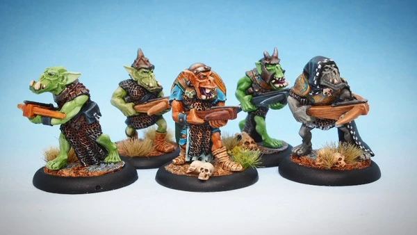 A group of four intricately painted orc miniatures stands against a light blue background. Each orc is armed with various hand weapons, showcasing a mix of colors and details in their armor and features. The miniatures are positioned on round bases adorned with small tufts of grass and skulls, highlighting their dynamic poses and unique characteristics.