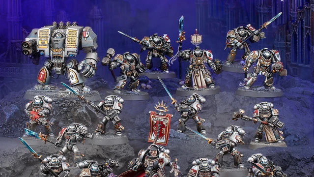 A detailed display of Black Templar miniatures showcases a variety of armored figures in silver and black, set against a dark, rocky backdrop. Prominent in the scene is a Venerable Dreadnought on the left, flanked by a mix of characters including the Emperor’s Champion, Bladeguard Veterans, and Sword Brethren, all wielding swords and other weapons. The figures are intricately painted, with some holding banners and others poised for battle, creating a dynamic and imposing presence.