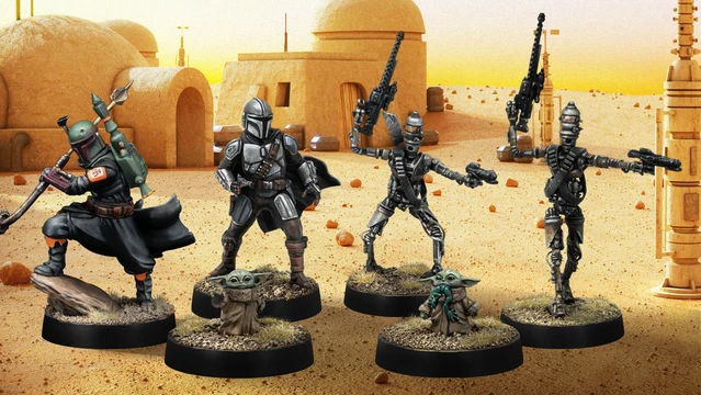 A group of four miniatures from the Star Wars universe is displayed against a desert backdrop featuring a simple structure. On the left, a character in a silver and black armor, resembling a bounty hunter, stands confidently. Next to him, two IG-Series Assassin Droids are posed with weapons drawn, showcasing their metallic bodies and intricate details. In the foreground, Grogu, a small figure with large ears, is depicted holding a small object, adding a whimsical touch to the scene. The ground is textured with grass and dirt, enhancing the overall aesthetic of the miniatures.