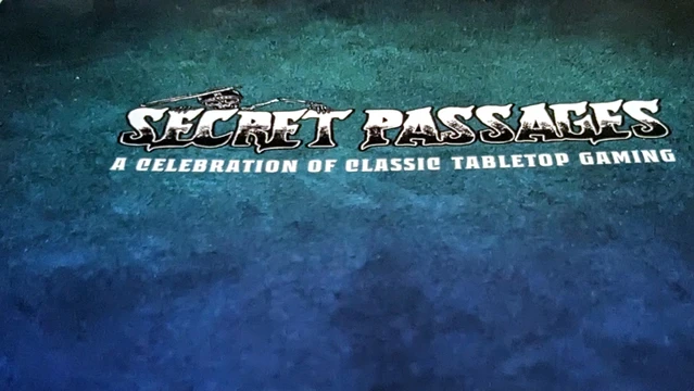 A close-up of the cover of "Secret Passages," featuring the title prominently displayed in bold, stylized lettering. The background has a textured, dark teal gradient, giving it a rich, immersive feel. Below the main title, the subtitle reads "Celebration of Classic Tabletop," also in bold, contrasting colors, emphasizing the theme of nostalgia and reverence for tabletop gaming history.