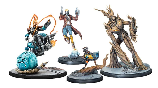 The image features four dynamic miniatures from the Marvel: Crisis Protocol - Guardians of the Galaxy Affiliation Pack. On the left, Cosmic Ghost Rider is depicted on a motorcycle, surrounded by fiery effects, while Star-Lord is shown mid-action, wielding his blasters. Rocket stands in a ready pose with a gadget, and Groot is presented in a towering, naturalistic form, showcasing intricate details in his bark-like texture. Each figure is mounted on a circular base, enhancing their display for tabletop gaming.