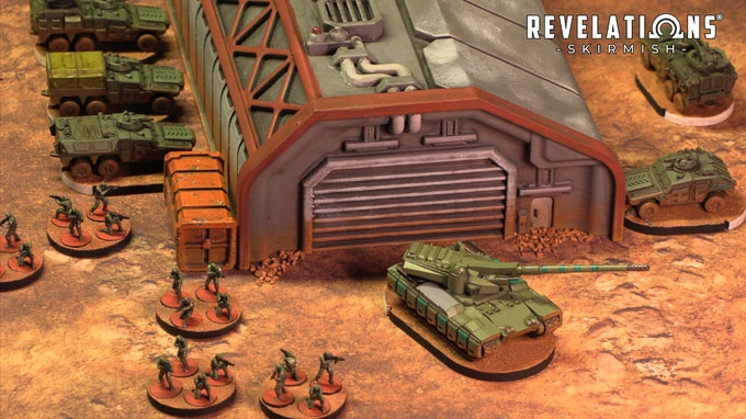 A detailed tabletop scene features a large, industrial building with a corrugated roof and a prominent garage door, set against a textured, sandy ground. In the foreground, several infantry miniatures are arranged in a semi-circle, while a green tank is positioned nearby, showcasing intricate details. Behind the building, additional vehicles are lined up, contributing to the military theme of the setting, with the "Revelations: Skirmish" logo visible in the top right corner.