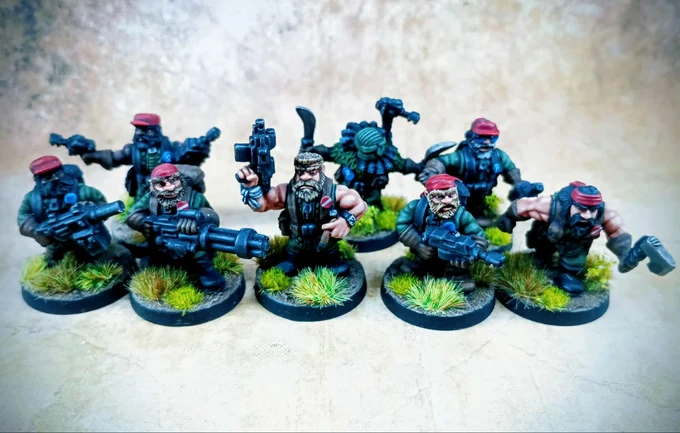 Eight miniatures of space dwarves are arranged in a semi-circle, each equipped with various weapons and wearing red berets. They stand on textured bases adorned with tufts of green grass, showcasing a rugged, military aesthetic. The figures display a mix of facial hair and expressions, emphasizing their character as jungle operatives.