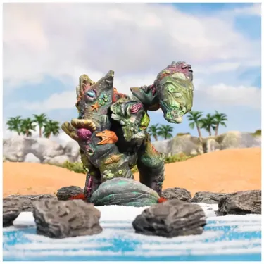 A colorful coral giant stands prominently in a coastal scene, adorned with various sea creatures like starfish and shells, showcasing a vibrant mix of greens, blues, and purples. The giant is positioned on a rocky outcrop near the water's edge, with a sandy beach and palm trees visible in the background. The overall setting conveys a fantastical marine environment, emphasizing the giant's unique design and connection to the ocean.