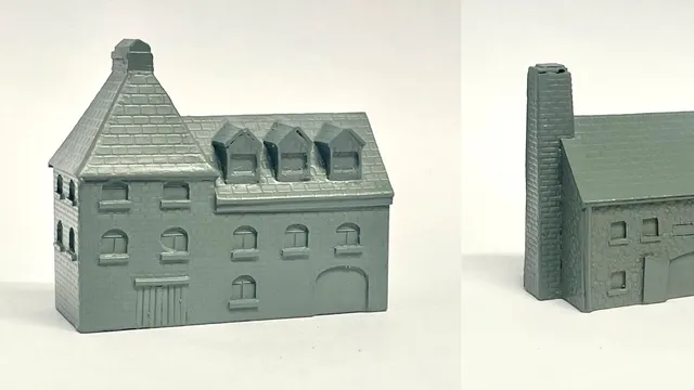 A detailed model of a building designed for 6mm scale wargames, featuring a sloped roof with three dormer windows and a textured surface that resembles slate. The facade includes several arched and rectangular windows, along with a large door at the base, all rendered in a light gray resin. The overall design suggests an industrial style, suitable for various historical or modern warfare settings.