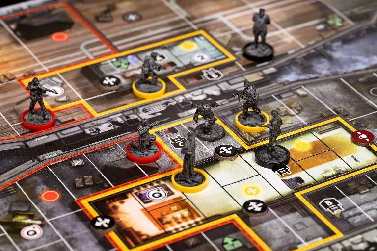 Board game with miniatures on a map featuring rooms, hallways, and tokens.