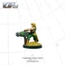 A miniature figure of a Commando Chain Gunner stands confidently, wielding a large chain gun. The figure is dressed in green tactical gear, with a headband and long blonde hair, and is positioned on a base with tufts of grass. The background is a simple grid pattern, emphasizing the figure's details and colors.