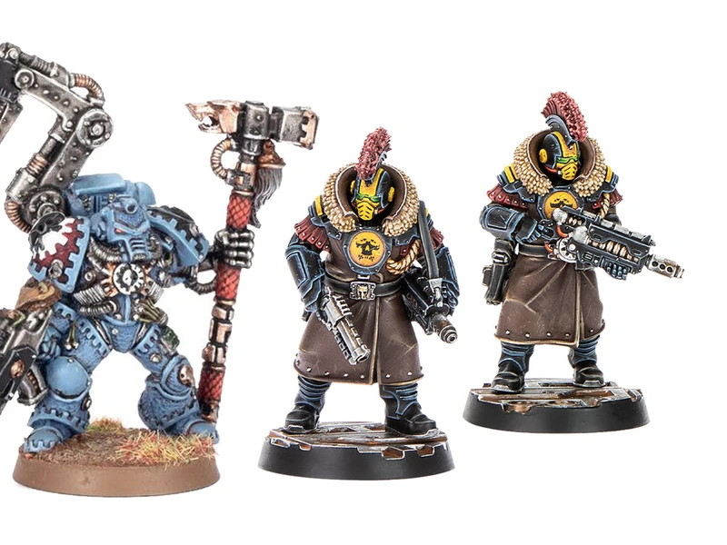 Three miniatures from the Palanite Enforcer Captains & Sergeants set are displayed. On the left, a figure wields a large axe and wears a blue and brown uniform with a fur collar, while the two figures on the right are equipped with firearms and feature distinctive yellow masks and red mohawks. All three are mounted on circular bases, showcasing intricate details in their armor and accessories.