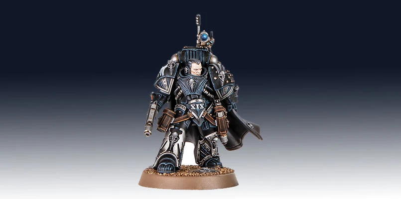 Kaedes Nex, the Moritat-Prime of the Raven Guard, stands prominently in the image, showcasing intricate details in his armor. He is clad in dark, metallic blue and silver, with a flowing black cape and various pouches and weapons attached to his belt. His helmet features a distinctive design, and he holds a weapon in one hand, while a small device is mounted on his shoulder, emphasizing his role in covert operations. The base is textured with a sandy finish, enhancing the overall presentation of this formidable character.