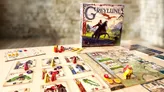 Board game Greylune box with illustrated knight on horse, surrounded by scattered cards showing characters, items, and buildings. Small wooden tokens and dice on table. Visible text: "Greylune" on box, "Le dragon rouge" on card.