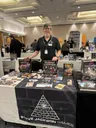 Man at a table with board games like Munchkin Shadowrun and Car Wars.