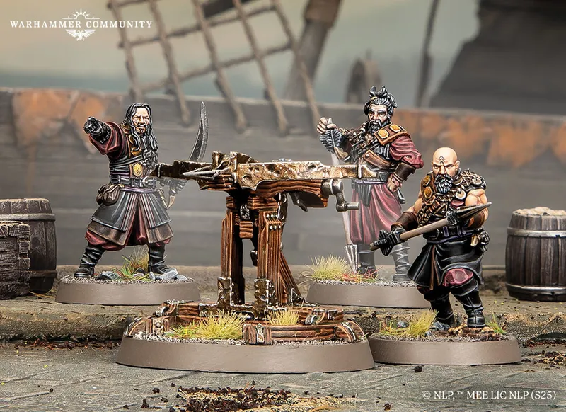 A detailed scene features a wooden Umbar ballista at the center, supported by a sturdy base and surrounded by tufts of grass. Flanking the ballista are three miniature corsairs, each dressed in dark, rugged attire, with one holding a sword and another gesturing with a hand raised. The background includes hints of a weathered environment, with barrels and a blurred structure, enhancing the atmosphere of a battle-ready setting.