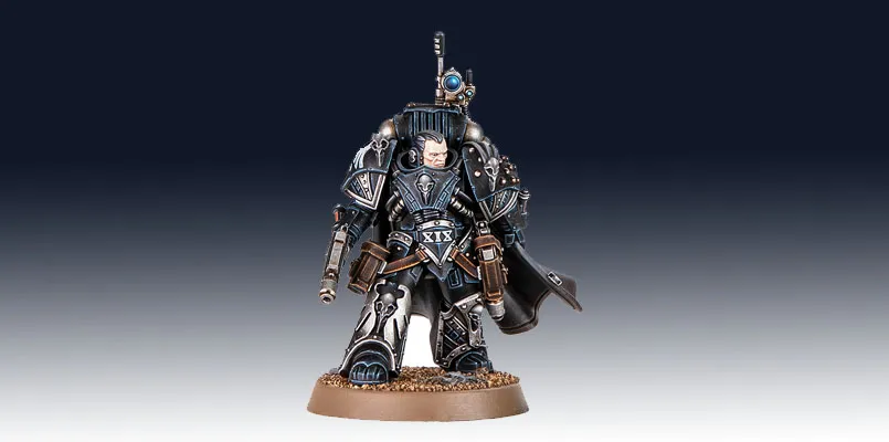 Kaedes Nex, the Moritat-Prime of the Raven Guard, stands prominently in the image, showcasing intricate details in his armor. He is clad in dark, metallic blue and silver, with a flowing black cape and various pouches and weapons attached to his belt. His helmet features a distinctive design, and he holds a weapon in one hand, while a small device is mounted on his shoulder, emphasizing his role in covert operations. The base is textured with a sandy finish, enhancing the overall presentation of this formidable character.