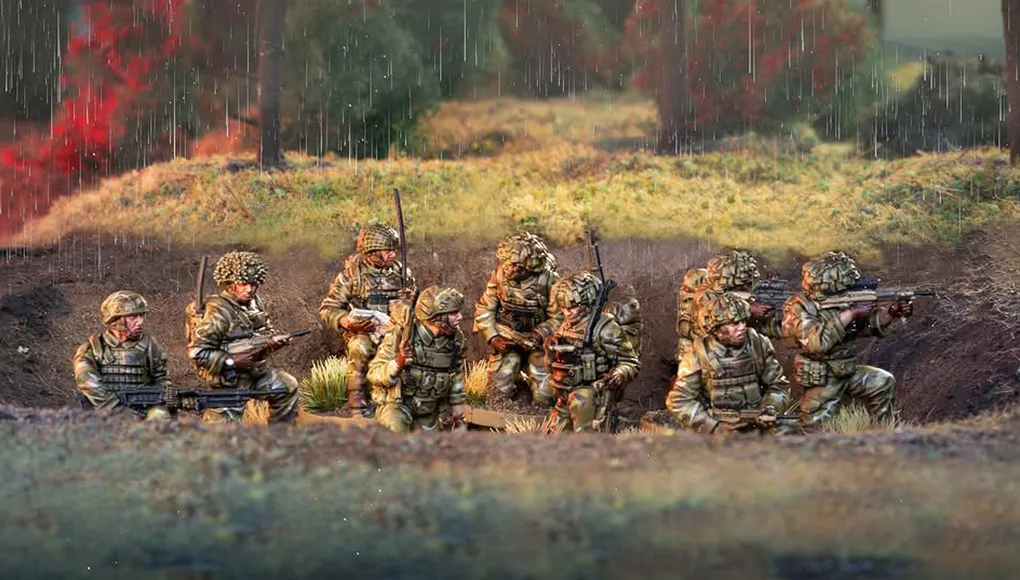 A group of six British army miniatures is depicted in a natural setting, with a backdrop of greenery and a hint of rain. The soldiers are dressed in modern camouflage uniforms and equipped with various weapons, including rifles and gear typical of contemporary military operations. They are positioned in a tactical formation, some seated and others standing, showcasing a range of unique sculpts that highlight their individual poses and details.