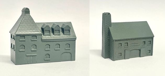 A detailed model of a building designed for 6mm scale wargames, featuring a sloped roof with three dormer windows and a textured surface that resembles slate. The facade includes several arched and rectangular windows, along with a large door at the base, all rendered in a light gray resin. The overall design suggests an industrial style, suitable for various historical or modern warfare settings.