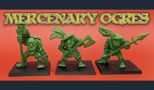 Three green ogre miniatures stand on black bases against a vibrant orange background. Each ogre has a distinct pose: the leftmost holds a staff, the center ogre wields an axe, and the rightmost brandishes a spear. They are adorned with details reminiscent of classic oldhammer styles, featuring exaggerated facial features and playful, dynamic designs. The text "MERCENARY OGRES" is prominently displayed above them in a bold, stylized font.