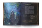 A character illustration of a "Street Rat" from the Blade Runner RPG book features a young person crouching against a colorful, graffiti-covered brick wall. The character has long, dark hair and wears a hooded jacket, embodying a gritty, urban aesthetic. Accompanying text provides details about the character's attributes, skills, and appearance, set against a dark, atmospheric background that enhances the dystopian theme.