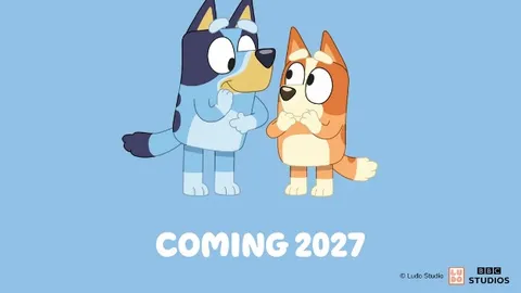 Two cartoon dogs, Bluey and Bingo, are featured prominently in the image. Bluey, a blue heeler, stands on the left with a playful expression, while Bingo, an orange heeler, is on the right, looking curious. Above them, the text "BLUEY AND CATAN" is displayed in bold, playful fonts, with "COMING 2027" at the bottom, all set against a light blue background.