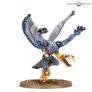 Miniature of a Greater Daemon of Tzeentch with blue-grey skin, golden wings, and ornate armor. Standing on a round base, holding a staff in one hand and a skull-like head in the other. Text in top right corner reads "Warhammer Community."