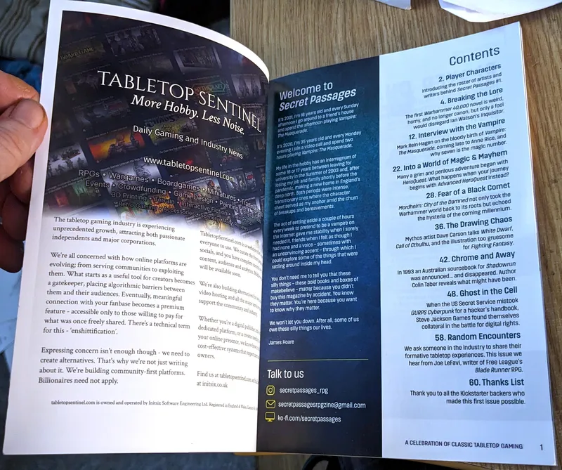 A hand holds open a magazine titled "Secret Passages," revealing two pages. The left page features an advertisement for "Tabletop Sentinel," promoting daily gaming and industry news, with a colorful collage of tabletop gaming images in the background. The right page introduces "Secret Passages," outlining its content and welcoming readers, with a list of articles and topics covered, including references to various tabletop games and cultural commentary. The overall design is clean and visually engaging, with a mix of text and imagery.