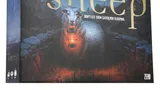 A board game box titled "The Sheep" features a menacing sheep holding a lantern, set against a dark, eerie forest backdrop. The title is prominently displayed in gold lettering, with the tagline "DON'T LET THEM CATCH YOU SLEEPING" beneath it. The overall color scheme is dark, with shades of blue and green, enhancing the horror-comedy theme of the game.