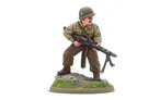 A 28mm scale miniature of a soldier, representing the war hero Audie Murphy, stands on a rocky base adorned with green grass. The figure is dressed in a light green military uniform with insignia on the sleeves and wears a helmet. He holds a machine gun in a ready position, showcasing a determined expression.