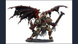 A large, intricately detailed statue of Angron, the Daemon Primarch of Khorne, stands prominently. He features massive, bat-like wings and a fierce expression, with a head that appears relatively small compared to his muscular body. Adorned with skulls and ornate armor, he wields a large sword in one hand and a weapon in the other, standing on a textured base that enhances the dramatic effect of the figure. The color palette includes deep reds, blacks, and metallic tones, emphasizing his menacing presence.