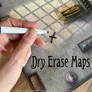 Hand marking an X on a tiled map with "Dry Erase Maps" text.