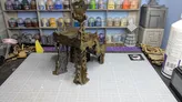 An Orc Lookout model is prominently displayed on a crafting mat, showcasing intricate details and a weathered appearance. In the background, a shelf holds various paint bottles, while additional terrain pieces and tools are visible on the workspace. The scene captures a creative environment focused on tabletop gaming and model building.