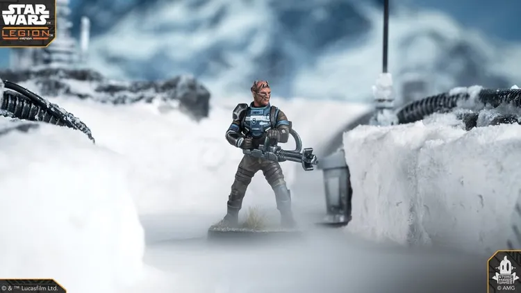 A detailed miniature of a character from the Star Wars universe stands prominently in a snowy landscape, holding a weapon with a focused expression. The character has distinctive features, including a unique head shape and is dressed in a blue and brown outfit with armor. In the background, blurred outlines of rocky terrain and a lantern can be seen, enhancing the atmospheric setting.
