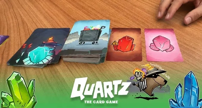 Stack of game cards with cart, gems, and robot illustrations, "QUARTZ THE CARD GAME" text.