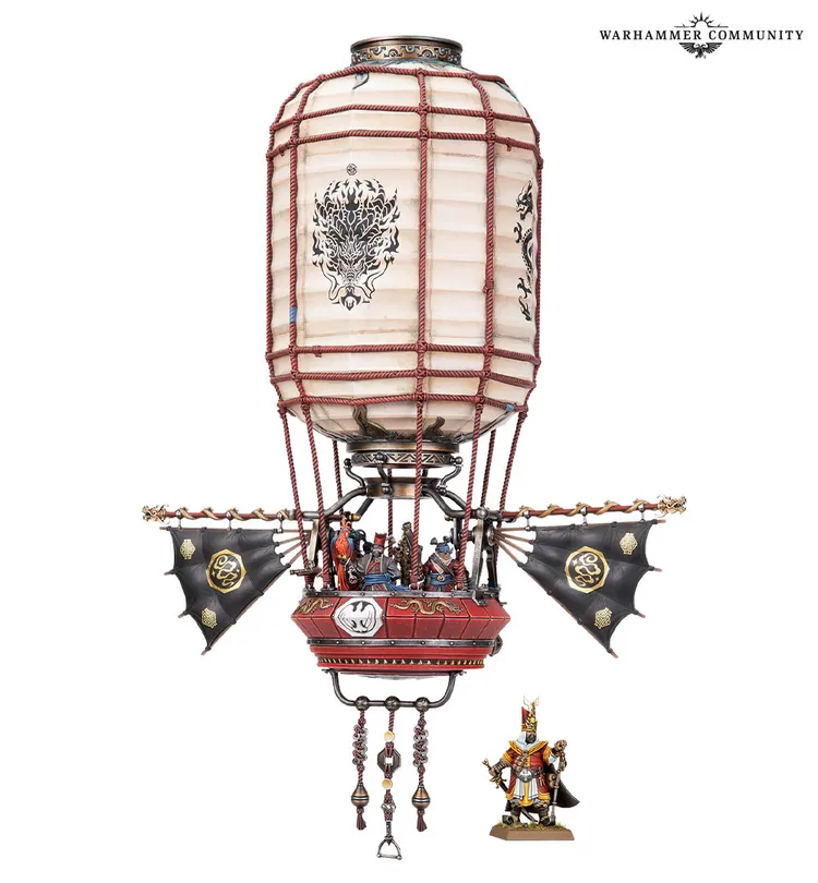 A detailed model of a Cathayan Sky Lantern, featuring a large, round lantern body wrapped in red rope, adorned with intricate designs. Below the lantern, a platform is equipped with sails and crew members, showcasing a mix of weaponry, including rifles and fire bombs. A small figure of a Cathayan general stands beside the lantern, highlighting the scale and intricacy of the model.