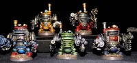 A group of five colorful, multipart miniatures representing armoured dwarves, each with distinct sci-fi and steam-driven designs. The miniatures feature various colors, including blue, green, red, and yellow, with intricate details like gears and pipes, and are equipped with different weapons. They stand on circular bases against a dark background, showcasing their unique character and craftsmanship.