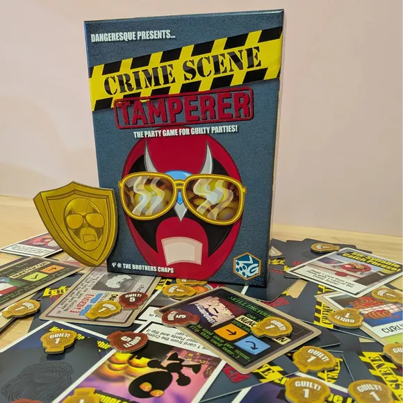 Crime Scene Tamperer game box with cards and tokens scattered on a wooden floor.