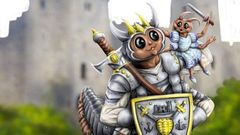 A whimsical illustration features a large, anthropomorphic creature resembling a knight, complete with armor and a crown, holding a shield adorned with a castle emblem. Perched on its shoulder is a smaller creature dressed in blue, while a tiny dragon-like figure stands beside them, also in armor. The background showcases a blurred castle and green grass, creating a playful and fantastical atmosphere.