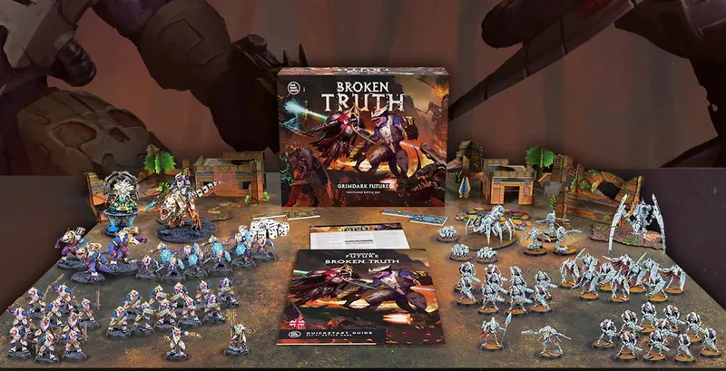 A large, detailed box titled "Grimdark Future: Broken Truth" is prominently displayed at the center, surrounded by various miniatures and game components. To the left, a collection of colorful plastic miniatures representing the Saurian Starhost is arranged, while to the right, the Robot Legions miniatures are showcased. Additional items include a quickstart guide, measuring tools, dice, and full-color terrain pieces, all set against a backdrop of a gaming mat and themed scenery.