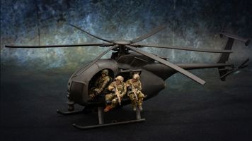 A detailed model of a Little Bird helicopter, featuring a dark color scheme, is prominently displayed. Two miniature soldiers are seated on the helicopter's skids, equipped with rifles, while another soldier is visible inside the cockpit. The background features a textured gradient, enhancing the focus on the helicopter and its crew.