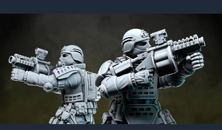 Two detailed miniatures from Anvil Industry's Special Forces range are positioned back-to-back, each holding futuristic firearms. The figures are clad in tactical armor with various pouches and equipment, showcasing a blend of sleek design and functionality. The miniatures are presented in a gray, unpainted finish, highlighting their intricate details and dynamic poses.