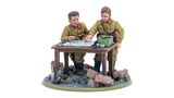 A detailed miniature scene features two Soviet officers, one with a map and the other pointing at it, engaged in strategic planning. They are dressed in military uniforms with insignia, standing beside a table cluttered with a map, a green box, and other items. The base is set on a rubble-strewn ground, with a small animal visible in the foreground, enhancing the war-torn atmosphere.