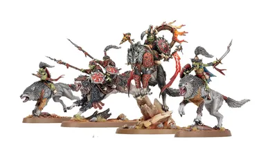 A dynamic display of goblin miniatures features several wolf-riding figures, including a prominent leader adorned with armor and a fiery banner. The miniatures are intricately detailed, showcasing vibrant colors and various weapons, set against a rocky base with tufts of grass. Additional wolf-riders and a chariot can be seen, emphasizing the theme of mobility and aggression in this new release.