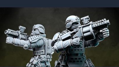 Two detailed miniatures from Anvil Industry's Special Forces range are positioned back-to-back, each holding futuristic firearms. The figures are clad in tactical armor with various pouches and equipment, showcasing a blend of sleek design and functionality. The miniatures are presented in a gray, unpainted finish, highlighting their intricate details and dynamic poses.