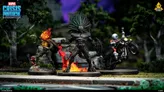 Two miniature figures on bases: one with a skeletal, armored design, glowing red flames on head and chest, holding a hammer, standing on a rocky surface; another with a muscular, black-skinned figure with a spiked helmet, flexing arms, surrounded by fire.