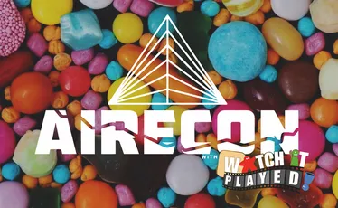 A colorful assortment of candies in various shapes and sizes serves as the backdrop for the event branding. The word "RECON" is prominently displayed in bold white letters, with a stylized triangular logo above it. Below, the text "with WATCH PLAYED" is featured in a playful font, suggesting a fun and engaging gaming event.