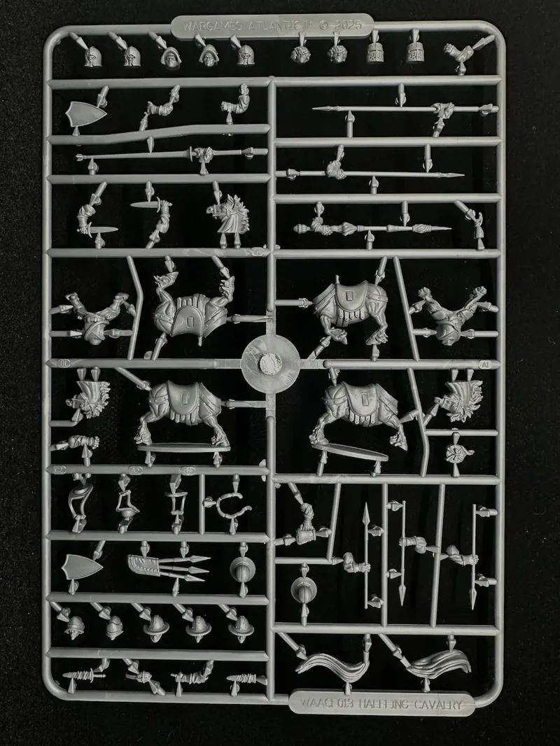 A sprue of plastic multipart miniatures featuring various components for halfling cavalry. The layout includes several halfling bodies, arms, and weapons, alongside stout pony figures. The pieces are intricately detailed, showcasing a variety of poses and accessories suitable for building a dynamic halfling army.