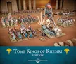 Miniature battlefield scene with two armies: one group of infantry and cavalry in white and blue armor with shields and spears, the other featuring a central skeletal figure with multiple arms, surrounded by smaller skeletal warriors. Terrain includes ruins with columns and scattered rocks.