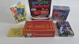 "gonuts for donuts!", "THINGS in RINGS", "Joking Hazard", "Regular Show FLUXX" board game boxes on a white surface.