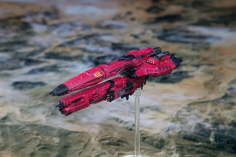 Red spaceship model on a stand over a blurred map background.
